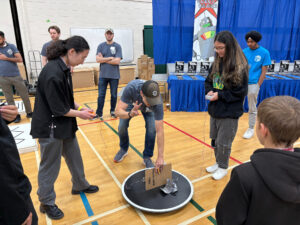 Two girls are ready for a mini sumo match, the volunteer is counting down to the match start.